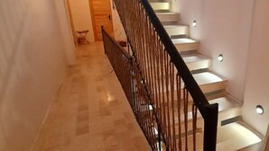 Uma escadaria com corrimão preto, degraus brancos e um aparelho de iluminação em cada degrau.