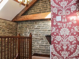 A stone wall, wooden staircase, and a patterned wallpaper.