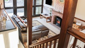Ein Wohnzimmer mit einer Couch, einem Kamin, einem Fernseher und Blick ins Freie.
