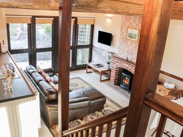 Una sala de estar con sofá, chimenea, televisor y vistas al exterior.