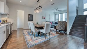 Une cuisine moderne avec un coin repas, un escalier et un salon comprenant un canapé et un fauteuil à motifs.