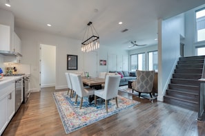 Una cocina moderna con comedor, una escalera y una sala de estar con sofá y sillón estampado.