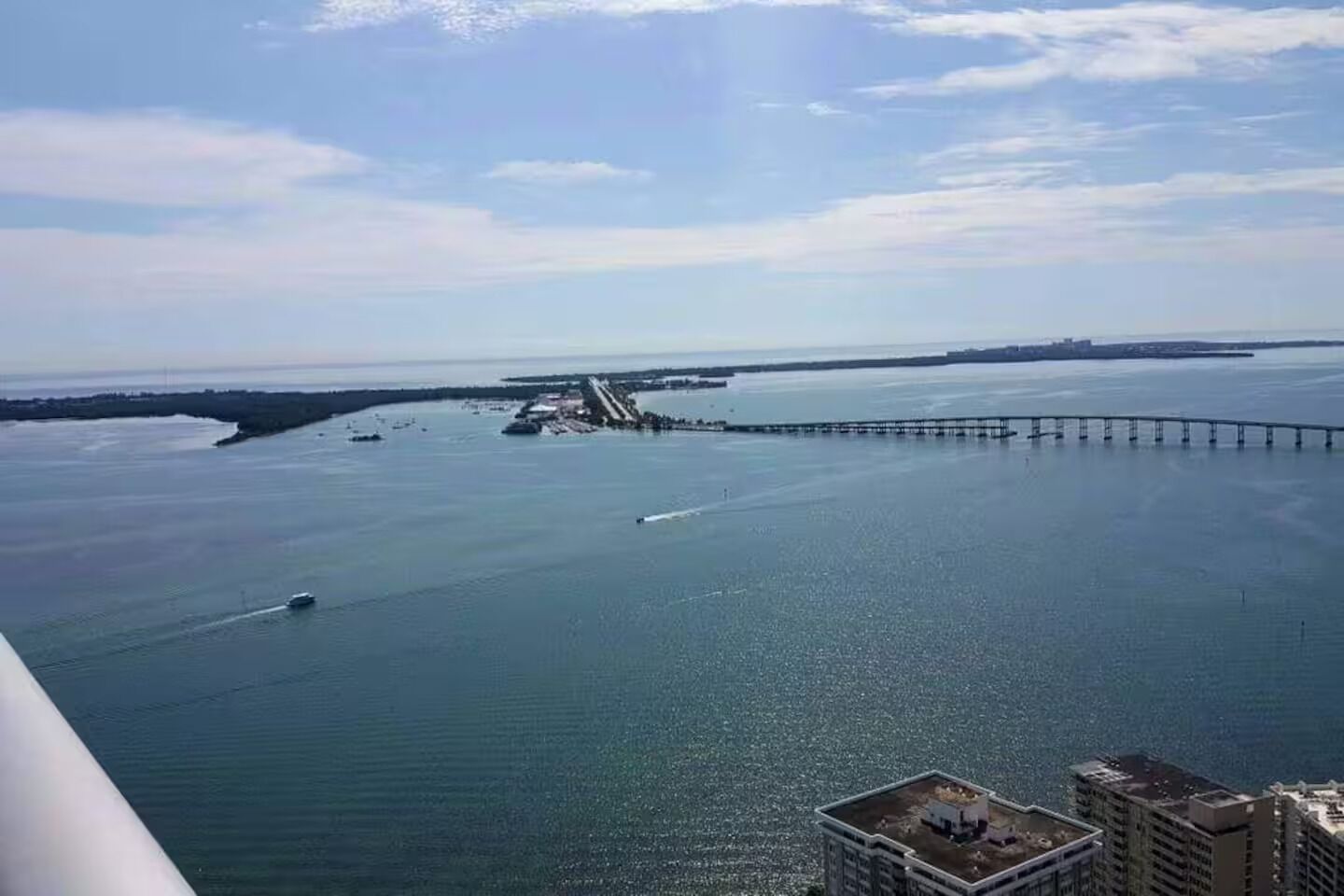 Vista costera con un puente, agua tranquila y edificios en primer plano.