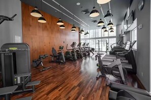 Ein Fitnessraum mit Trainingsgeräten, Holzwänden und Pendelleuchten.