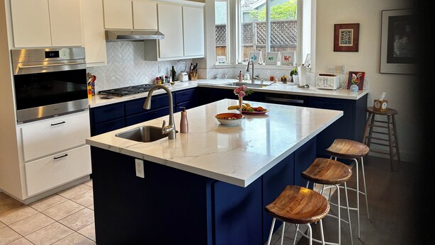 Een moderne keuken met een centraal eiland, roestvrijstalen apparatuur en uitzicht op de omgeving.