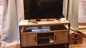 Ein Fernseher auf einem Holzboden mit Fernbedienung, Tastatur und Taschentuchbox.