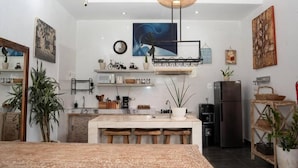 A modern kitchen with a central island, white cabinetry, and various kitchen appliances. - Cozzy Villa Devine (Canggu)