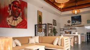 A modern living room with a sofa, coffee table, and artwork on the walls. - Cozzy Villa Devine (Canggu)