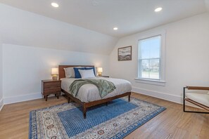 A bedroom with a bed, bedside tables, a window, and a view.