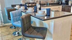 A kitchen with a central island, bar stools, and a stainless steel range hood. - Blue Pearl Walk to Beach Sleeps 9 New Golf Cart Option (Bolivar Peninsula)