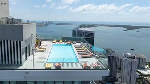 Ein Pool auf dem Dach mit Liegestühlen und Blick auf Stadt und Wasser.
