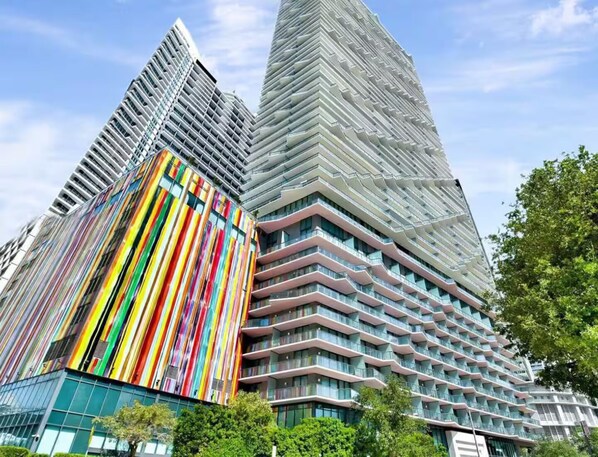 Ein modernes Hochhaus mit markanter Fassade und einem farbenfrohen, vertikalen Streifenmuster.