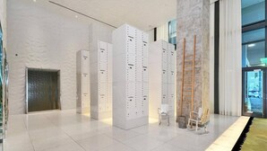 Un hall d’entrée moderne avec des casiers blancs, une échelle en bois et une porte en verre donnant sur l’extérieur.
