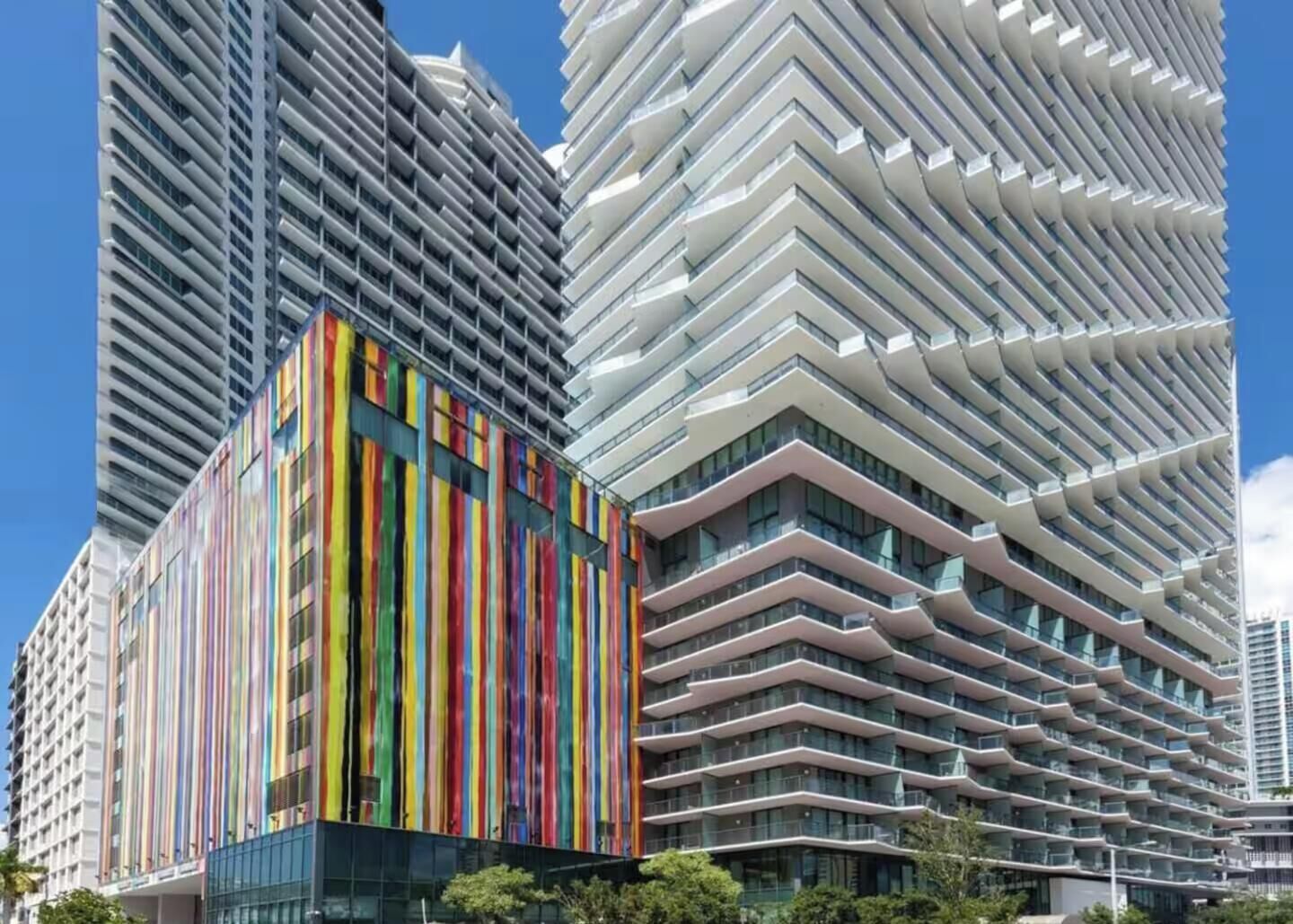 A modern high-rise building with a distinctive zigzag facade and a colorful vertical stripe pattern on one side.
