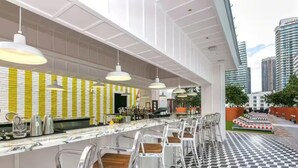 Un espace bar moderne avec un sol à carreaux, des tabourets de bar et des luminaires suspendus.