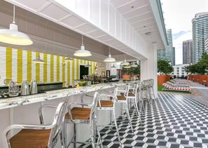 Eine moderne Bar mit Schachbrettboden, Barhocker und Pendelleuchten.