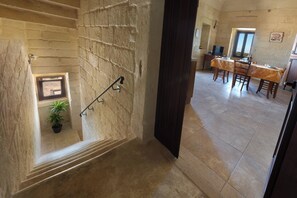 Una escalera con barandilla, una planta en maceta y un comedor con mesa y sillas.