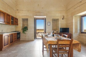 Una cocina con armarios de madera, una mesa de comedor con mantel y un televisor.