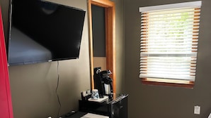 Una habitación pequeña y moderna con escritorio, silla y televisión de pantalla plana montada en la pared.