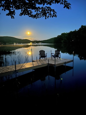A calm lake at dusk with a wooden dock and two chairs facing the water.. Berkshire Lake Lodge