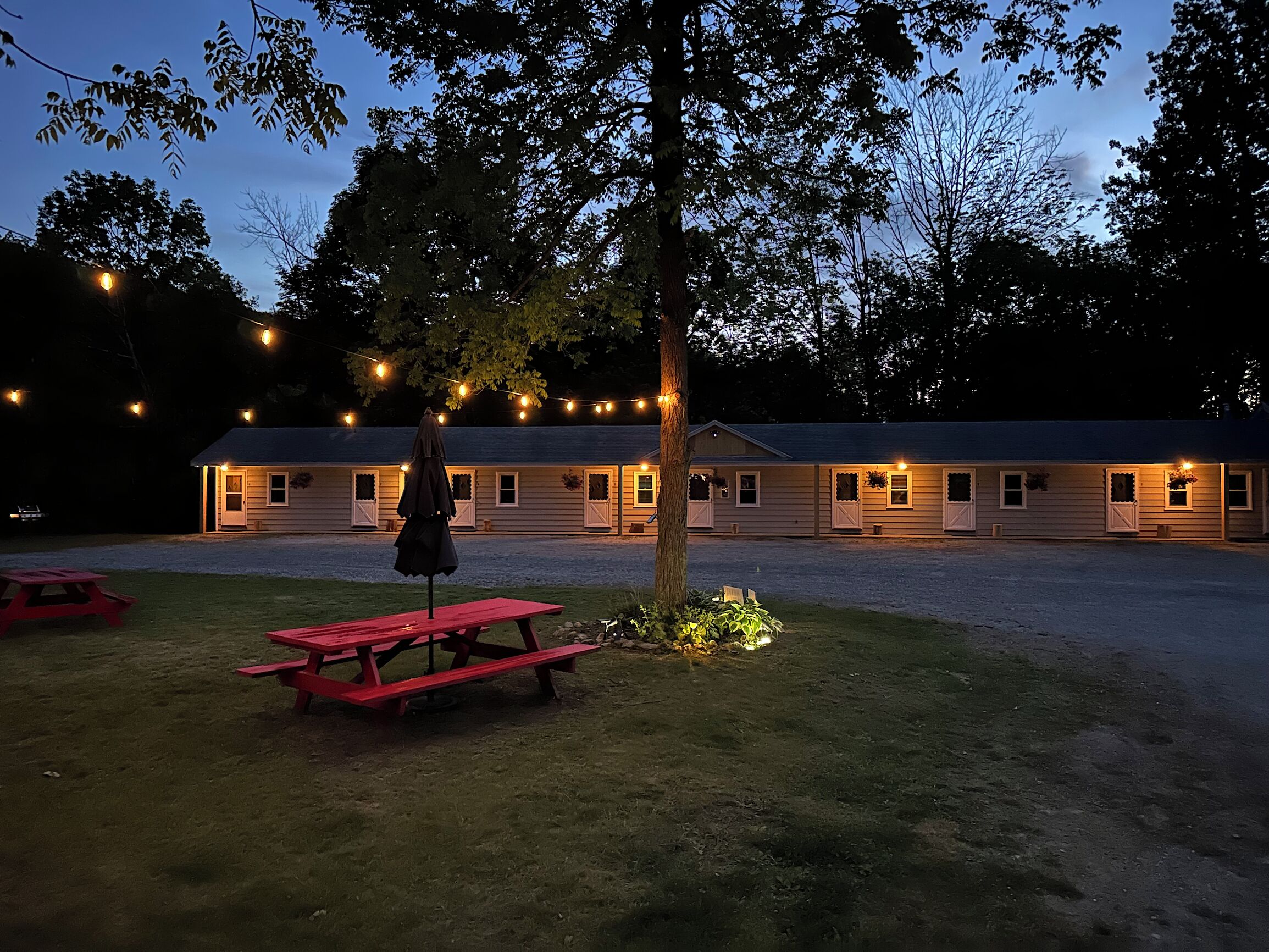 A building with multiple windows and a covered outdoor area with picnic tables.