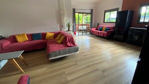 A living room with a sectional sofa, a dining table, a washing machine, and a sliding glass door leading to an outdoor area. - La Casa 974 (Saint-Pierre)