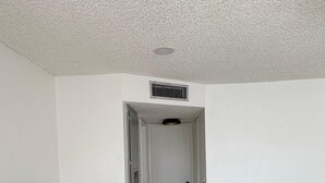 A hallway with a television on a white stand, a wooden table with a tray, and a door at the end. - 2Bed1Bath Mostaccioli KingQueenBeds CentralPhoenix (Phoenix)