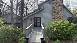 A house with a stone chimney, a wooden door, and a pathway leading to the entrance. - The Stone & Bridge: Close to MKT Trail & Dog Park, Dining, Groceries & I-70 (Columbia)