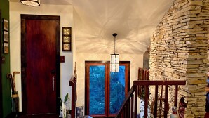 A staircase with a stone wall, a wooden door, and a window with a view of trees. - The Stone & Bridge: Close to MKT Trail & Dog Park, Dining, Groceries & I-70 (Columbia)