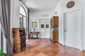 Un couloir avec un meuble à vin, une machine à coudre, une table avec une plante et une porte.
