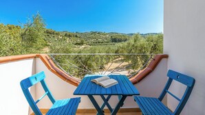 Ein Balkon mit Tisch, Stühlen, einem Buch und Blick auf eine hügelige Landschaft.