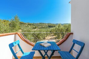 Un balcon avec une table et des chaises, un livre et une vue sur un paysage vallonné.
