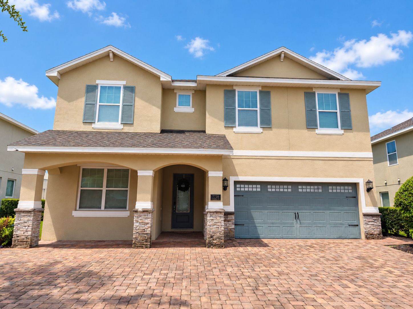 A two-story house with a garage, a front entrance with a door, and a brick driveway.