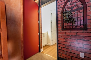 A hallway with a red door, a white door, and a brick wall with a decorative iron gate. - Stupendous Disney Vacation Home W Private Pool (Kissimmee)