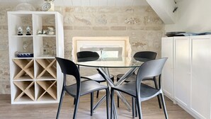 Ein Essbereich mit einem Glastisch, vier Stühlen, einem weißen Schrank und einem Weinkühlschrank.