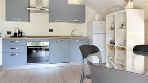 Eine moderne Küche mit grauen Schränken, einem eingebauten Backofen und einem weißen Kühlschrank.