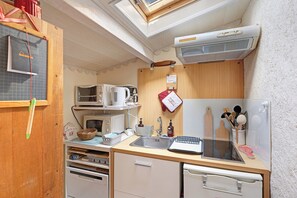 A compact kitchen with a microwave, kettle, and a small sink.