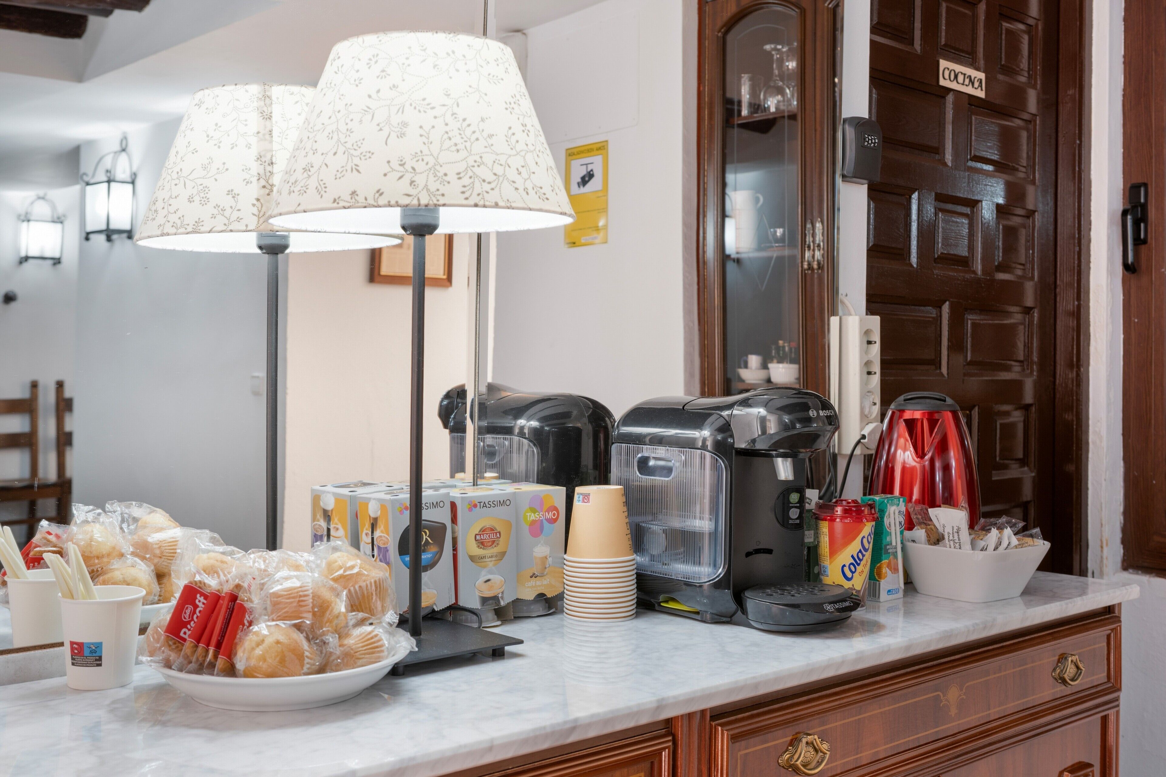 Een keukentafel met koffiezetapparaten, een lamp en verpakte etenswaren.