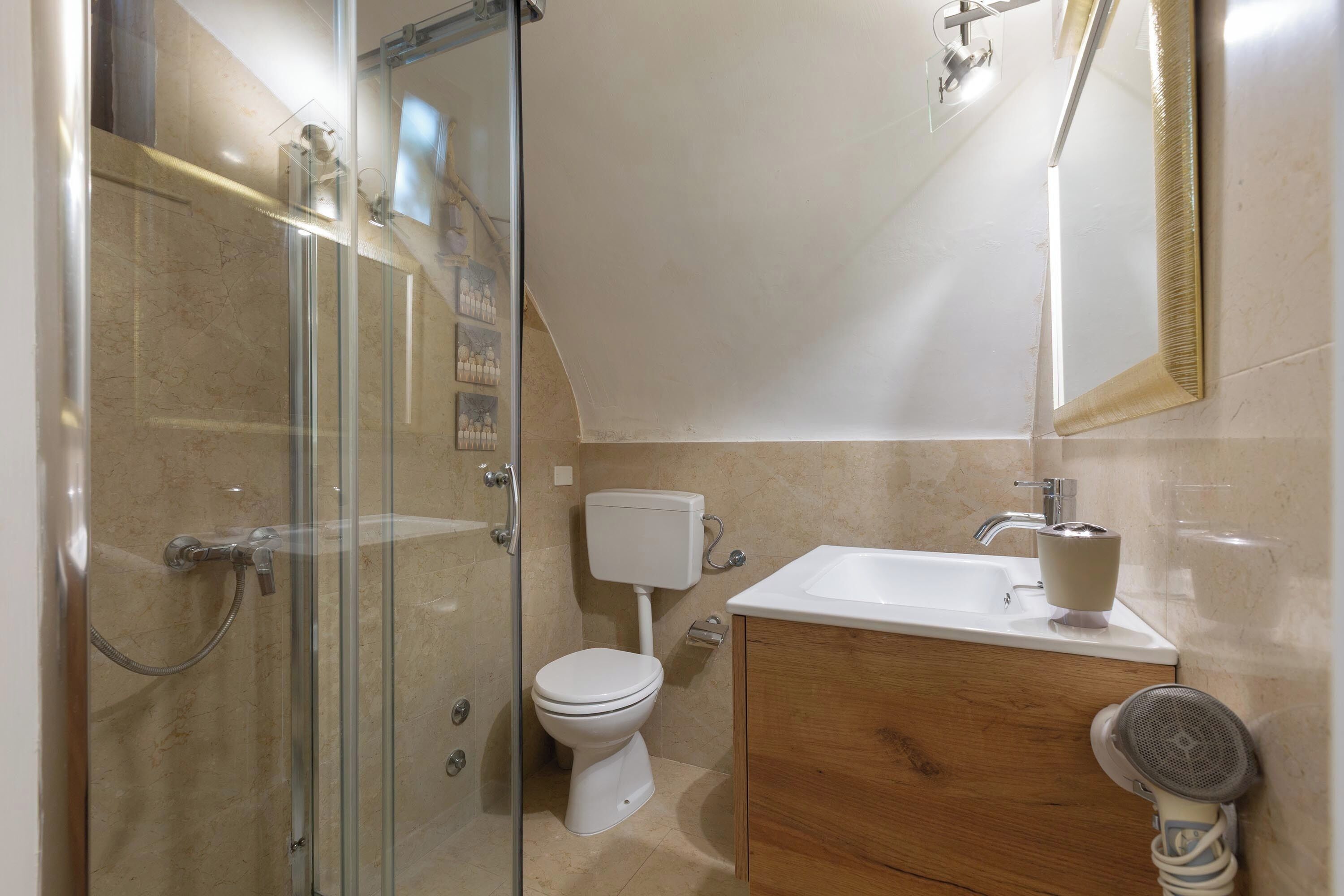 A bathroom with a glass-enclosed shower, a toilet, a sink, and a mirror.