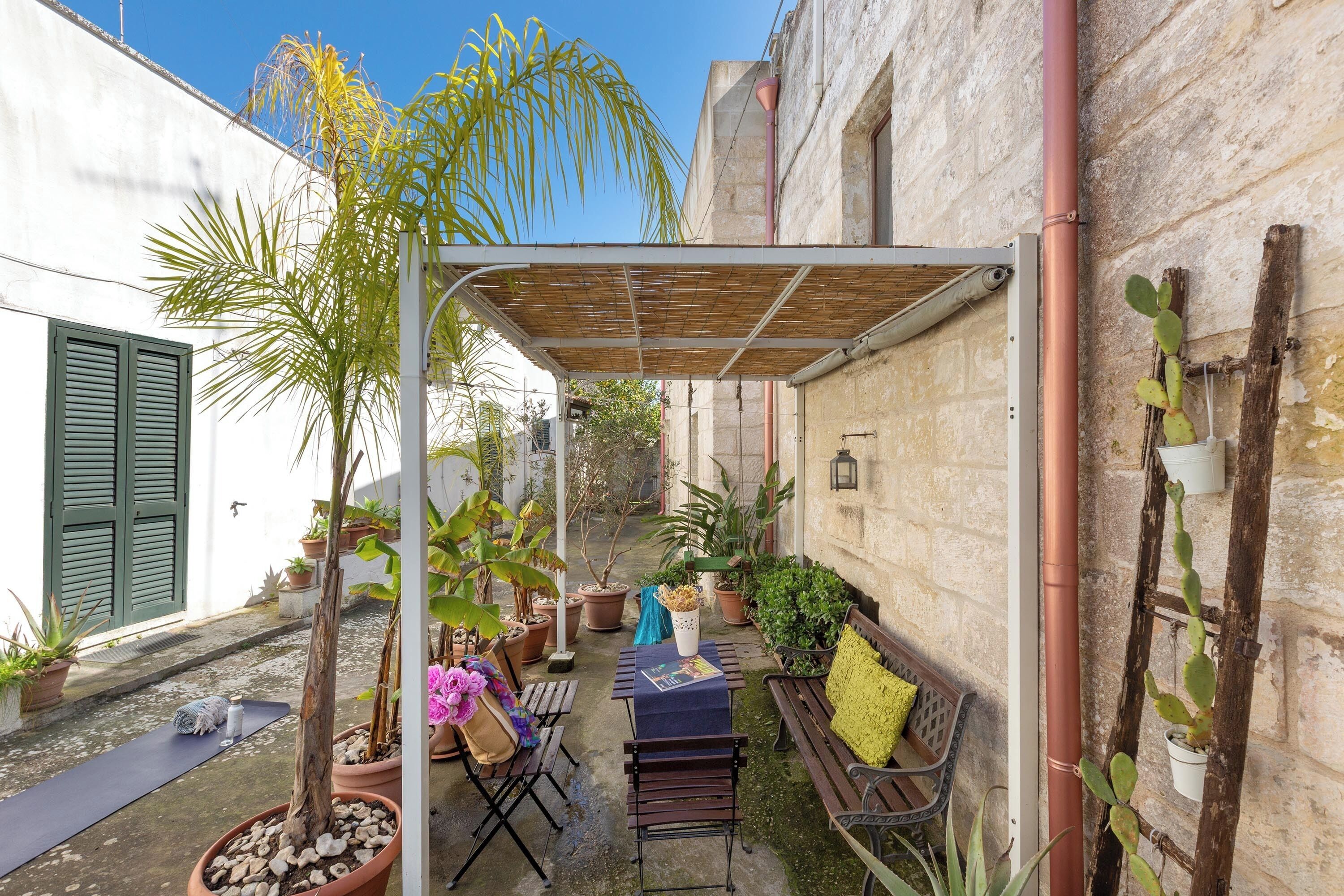 A courtyard with a covered seating area, potted plants, and a bench.