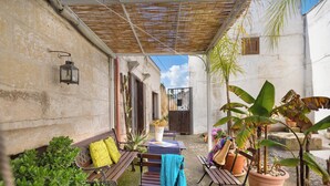 Eine Terrasse im Freien mit Tisch, Stühlen und Kübelpflanzen.