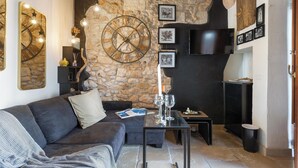 Ein gemütliches Wohnzimmer mit Steinwand, einer großen Uhr und einem an der Wand befestigten Flachbildfernseher.