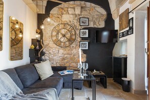 Ein gemütliches Wohnzimmer mit Steinwand, einer großen Uhr und einem an der Wand befestigten Flachbildfernseher.