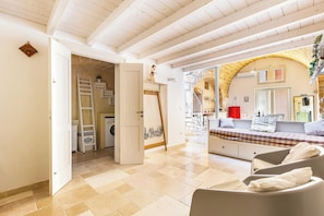 A spacious room with a large bed, a seating area with chairs, a laundry area, and a view of an outdoor terrace. - Casa del Grano by BarbarHouse (Alessano)
