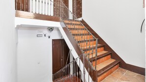 Una escalera de madera con barandillas de metal que conduce a una plataforma con una puerta.