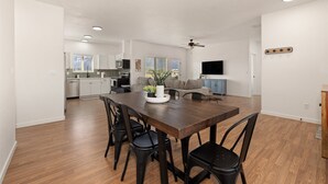 A spacious living area with a dining table, chairs, a sofa, and a television.
