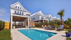 Une maison à deux étages avec une piscine, du mobilier d’extérieur et une terrasse en bois.