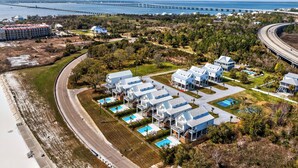 Un hôtel situé sur la côte, composé de plusieurs bâtiments, doté d’un espace piscine et offrant une vue sur l’océan et un pont situé au loin.