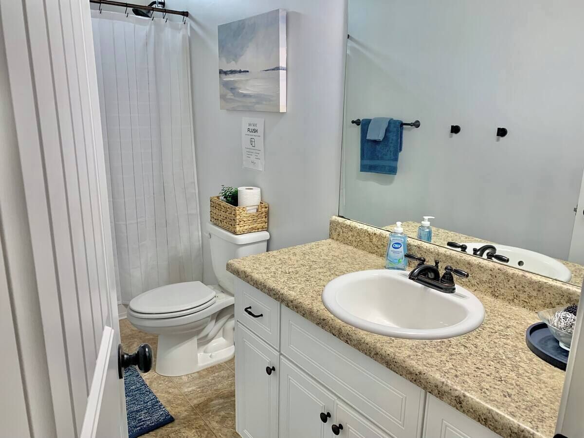 Baño con inodoro, lavamanos y cortina de ducha.