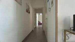 Un couloir avec un lit en arrière-plan, un téléphone et un téléviseur posé sur un meuble.